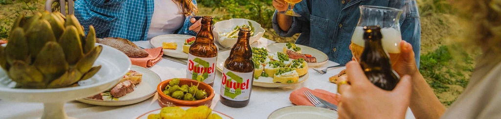 tavola imbandita con cibo e duvel tripel hop citra